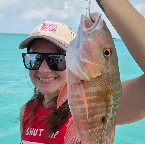 Angler holding a king mackerel over calm turquoise water
