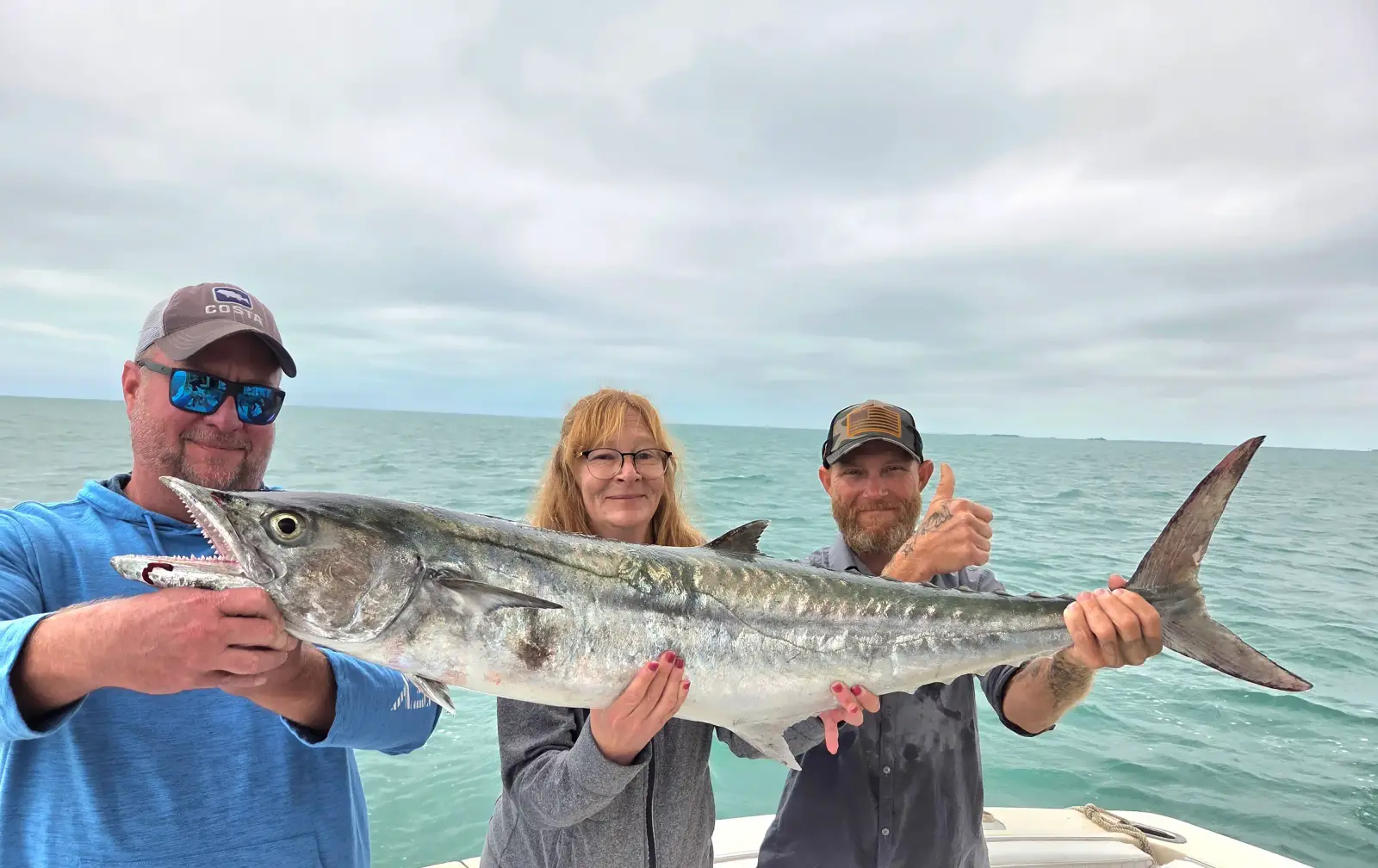 Three anglers holding a large king mackerel caught near Key West