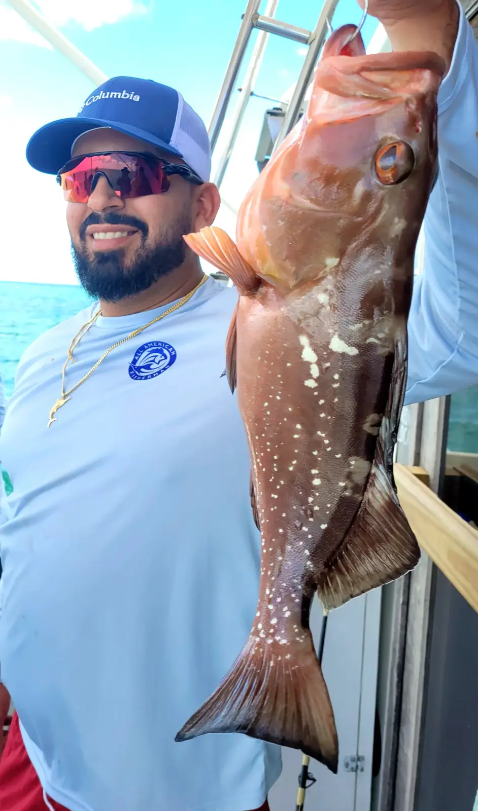 A couple holding a red grouper aboard the Magic