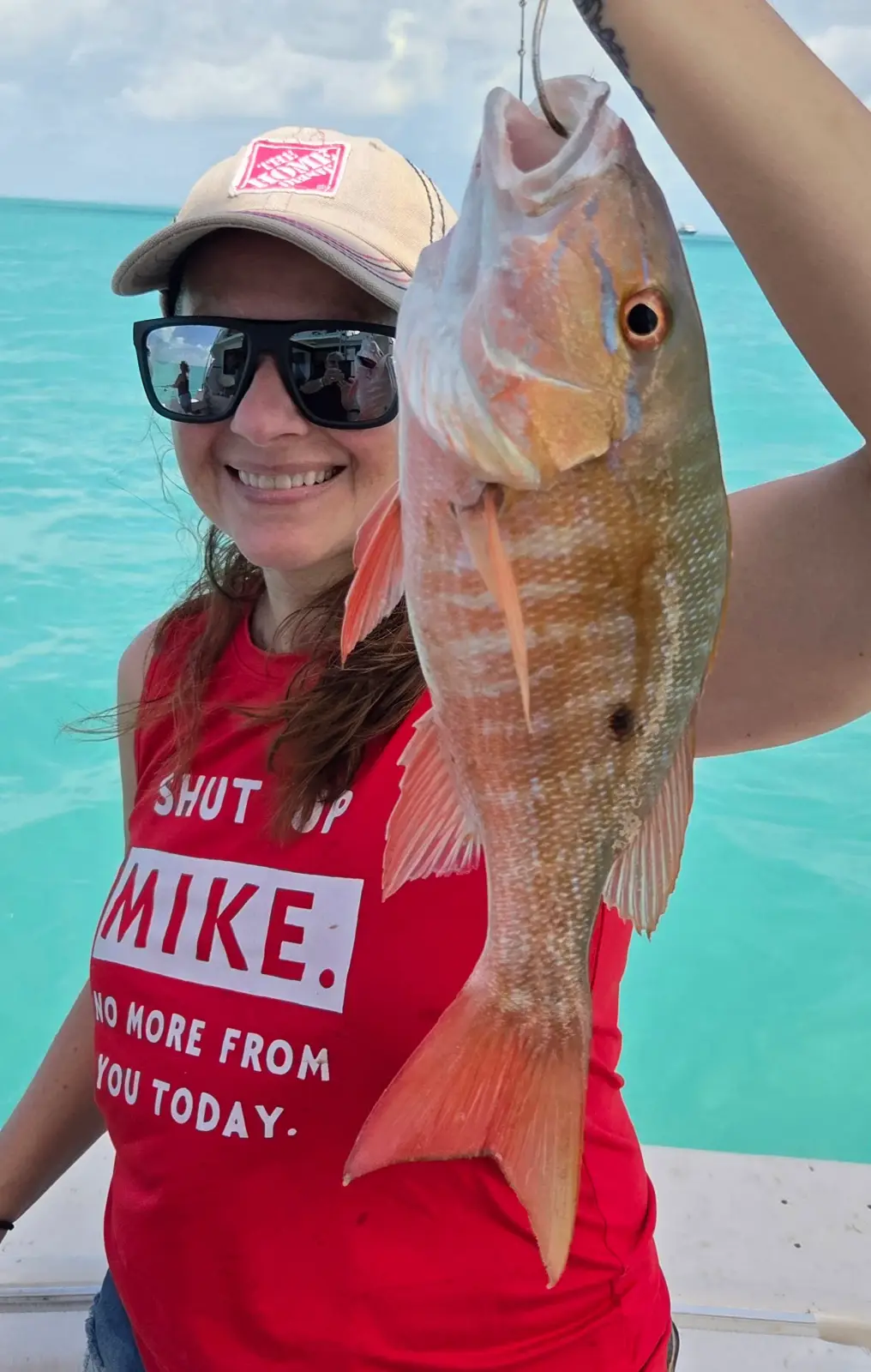 A group of seven guests and their dog posing with a mutton snapper on the Magic