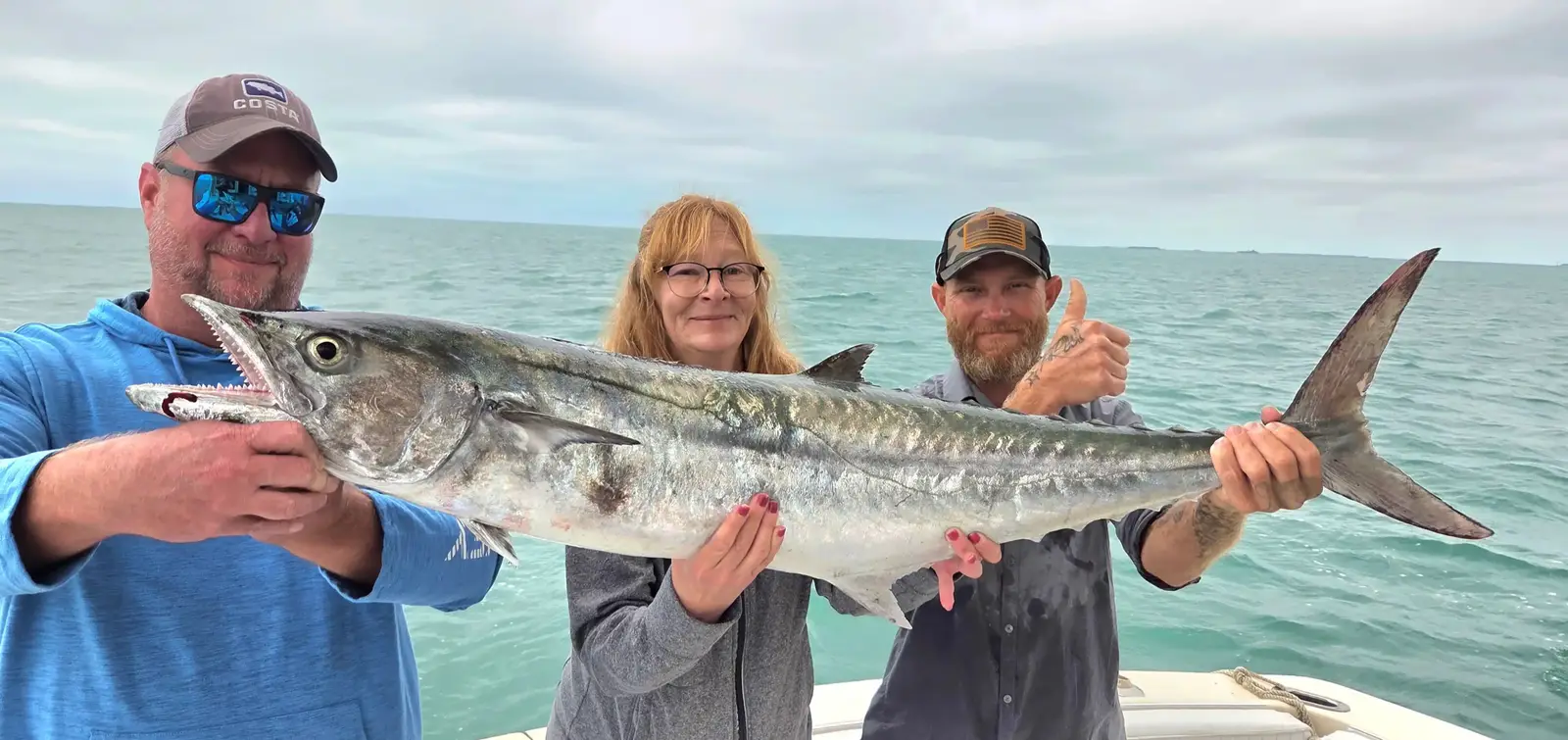 Three anglers holding a large king mackerel caught on a morning charter in Key West