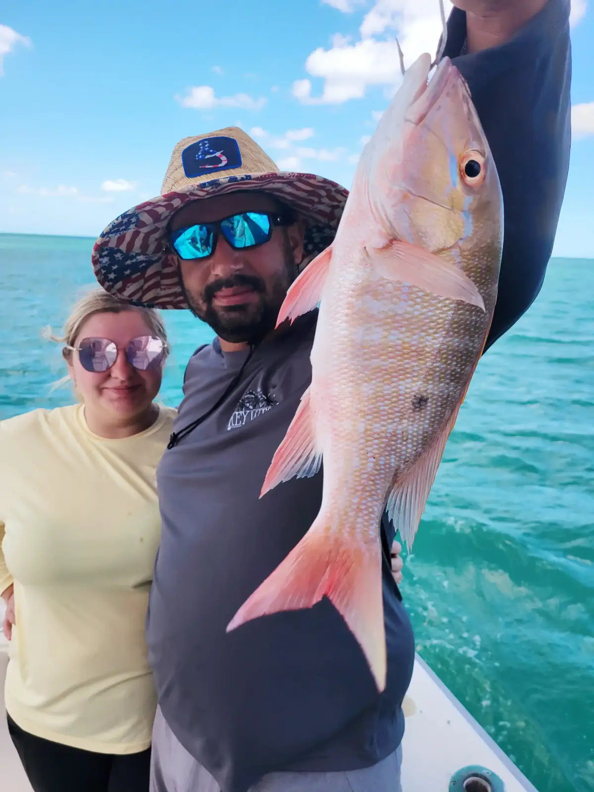 A couple holding a mutton snapper aboard the Magic