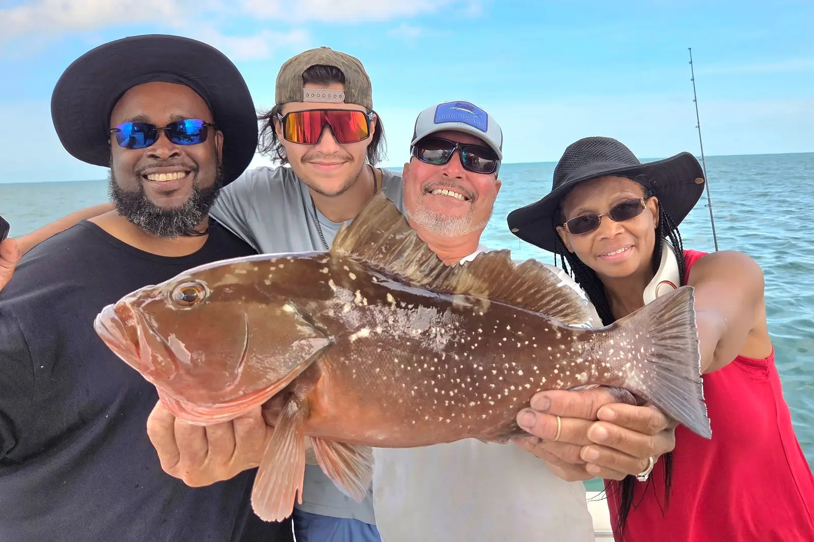 A group of four guests holding a grouper on an afternoon charter in Key West